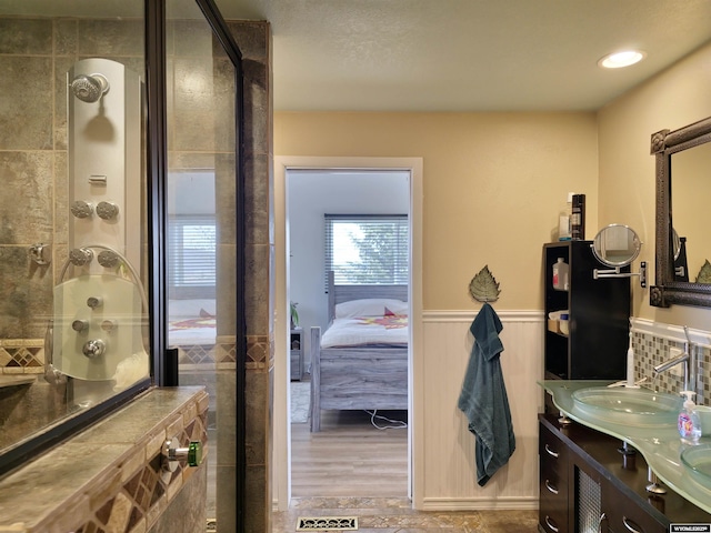 ensuite bathroom featuring wainscoting, ensuite bath, vanity, and a stall shower