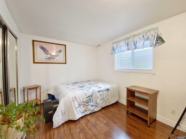 bedroom with baseboards, wood finished floors, and a closet