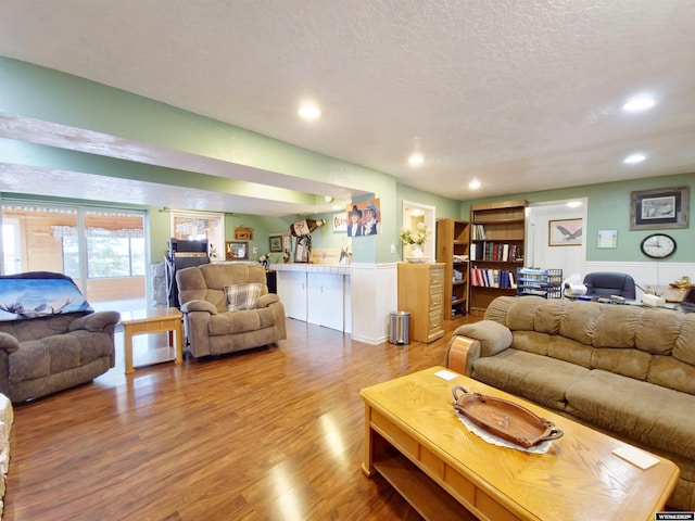 living room with recessed lighting, wood finished floors, a textured ceiling, and wainscoting