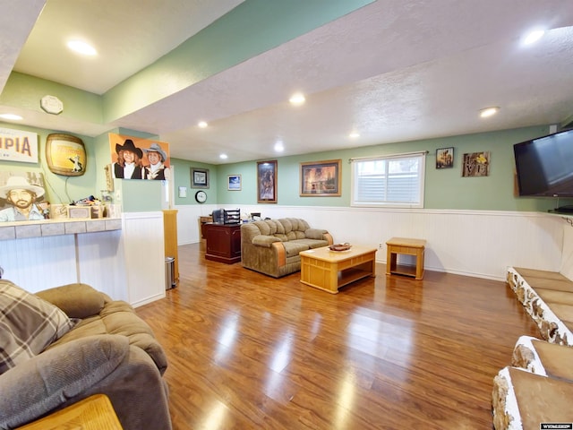 living area with a wainscoted wall, wood finished floors, and recessed lighting