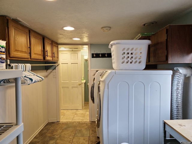 clothes washing area featuring baseboards, recessed lighting, separate washer and dryer, stone finish floor, and cabinet space