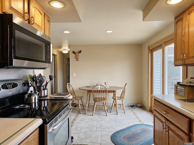kitchen featuring stainless steel appliances, baseboards, recessed lighting, brown cabinetry, and light countertops
