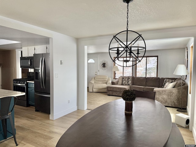 dining area featuring baseboards, a notable chandelier, a textured ceiling, and light wood-type flooring