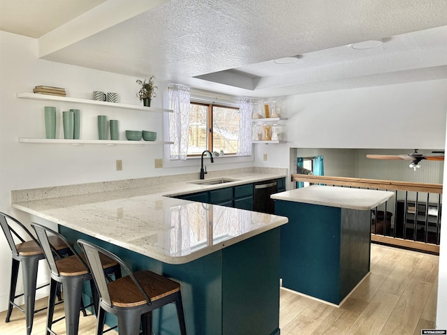 kitchen with a peninsula, a sink, open shelves, dishwasher, and a kitchen island