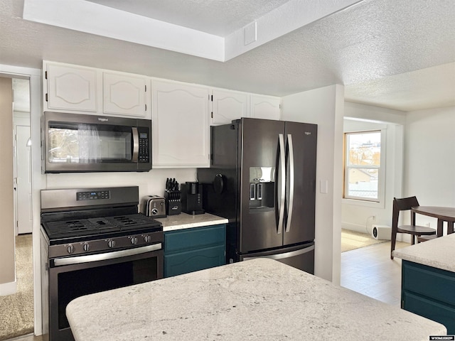 kitchen with a textured ceiling, white cabinetry, baseboards, and stainless steel appliances