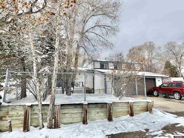 view of snow covered exterior featuring fence and driveway