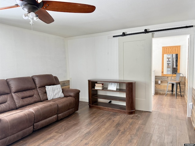 living room featuring wood finished floors, ceiling fan, and a barn door