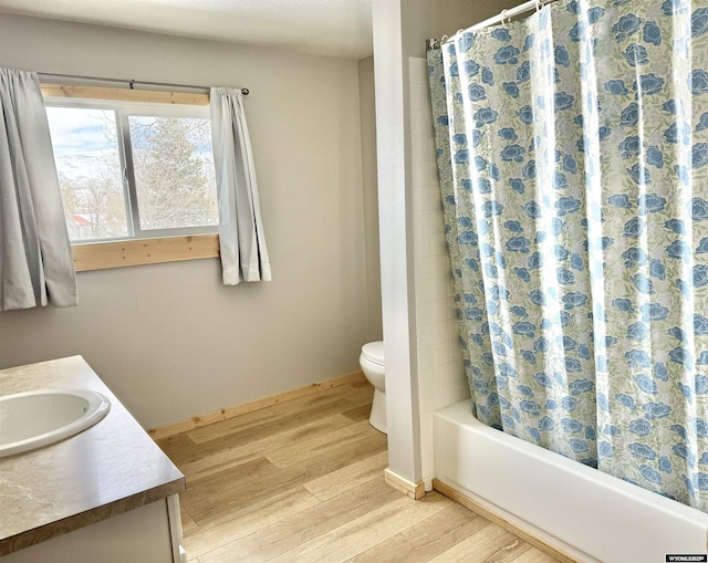 full bathroom featuring shower / bath combination with curtain, wood finished floors, toilet, vanity, and baseboards