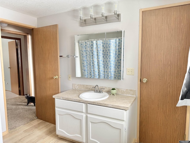 bathroom featuring a shower with shower curtain, wood finished floors, a textured ceiling, and vanity