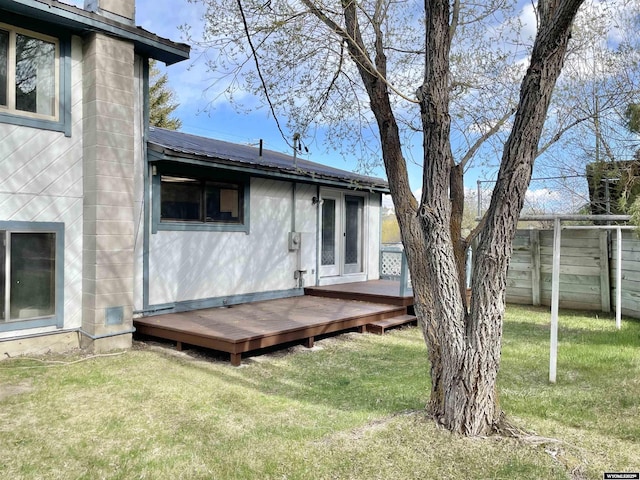rear view of house with fence, a yard, and a deck