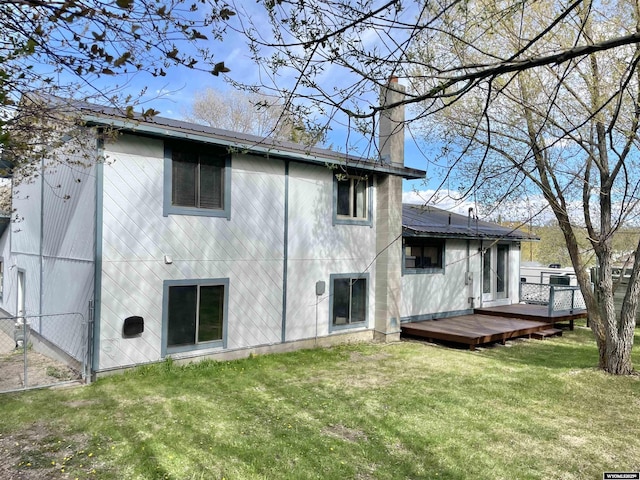 rear view of house with fence, a lawn, a chimney, and a deck