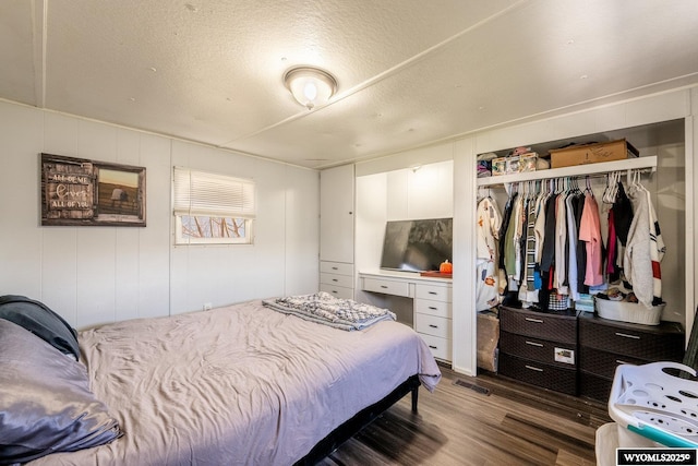 bedroom featuring a textured ceiling, wood finished floors, visible vents, and a closet