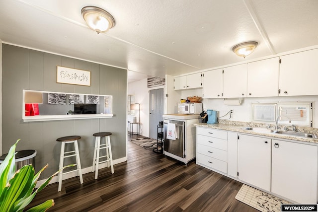 kitchen featuring a sink, dark wood finished floors, white microwave, white cabinetry, and washer / clothes dryer