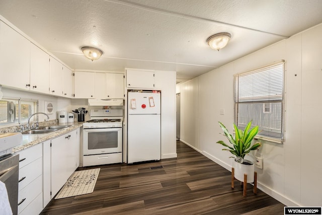 kitchen featuring a sink, baseboards, white cabinetry, white appliances, and dark wood-type flooring