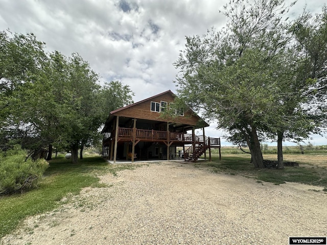 exterior space with a wooden deck, gravel driveway, and stairs