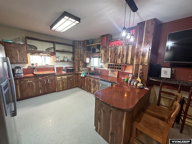 kitchen with stainless steel appliances, open shelves, dark countertops, a sink, and a peninsula