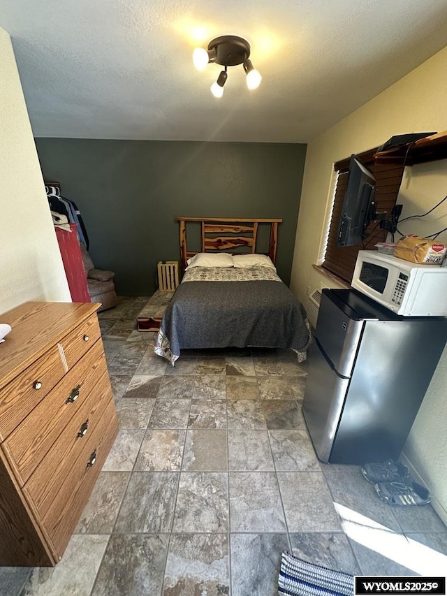bedroom featuring freestanding refrigerator and stone finish floor