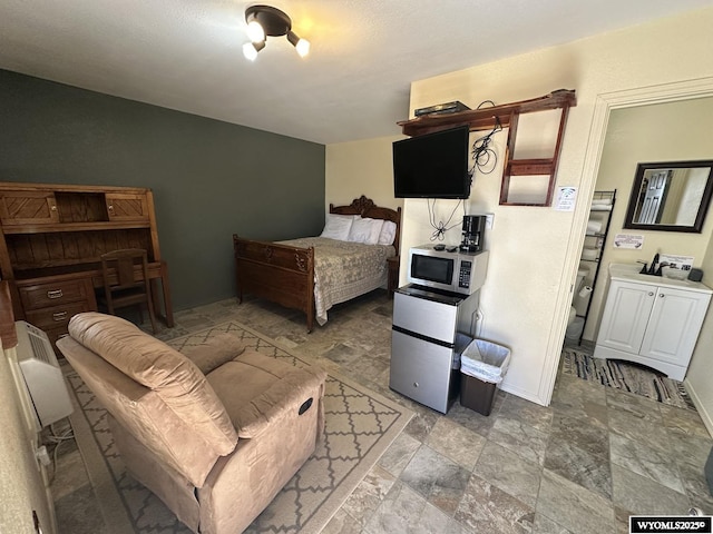 bedroom featuring refrigerator, stone finish flooring, and baseboards