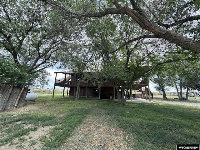 back of property with a wooden deck, a lawn, and stairs