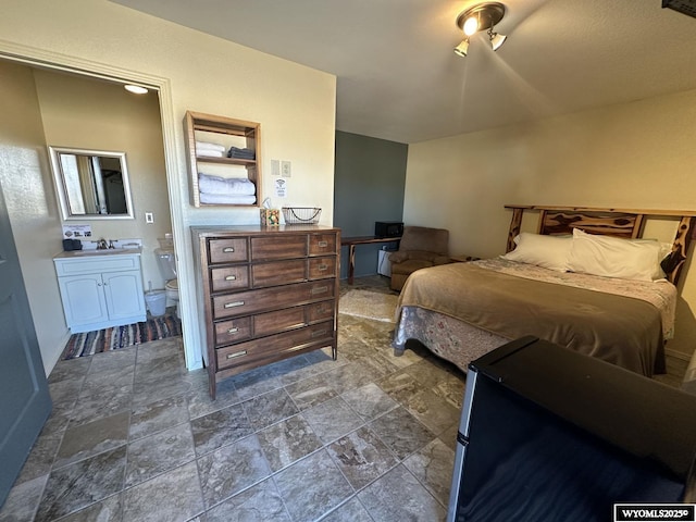 bedroom featuring ensuite bathroom, a sink, and stone finish flooring