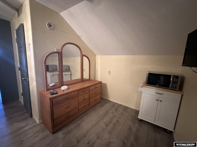 bedroom with lofted ceiling, baseboards, and dark wood-style floors