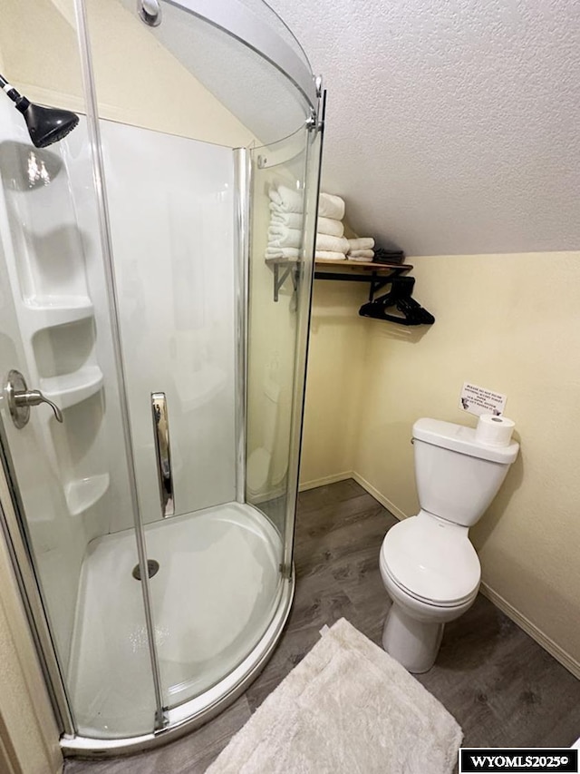 bathroom featuring a textured ceiling, toilet, a stall shower, baseboards, and wood finished floors