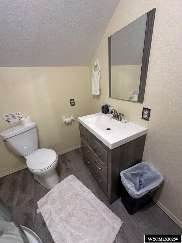 half bathroom featuring wood finished floors, a textured ceiling, toilet, and vanity