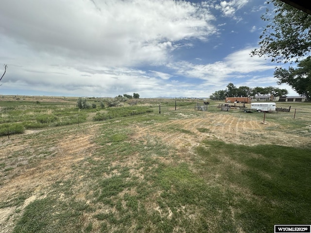 view of yard with fence and a rural view
