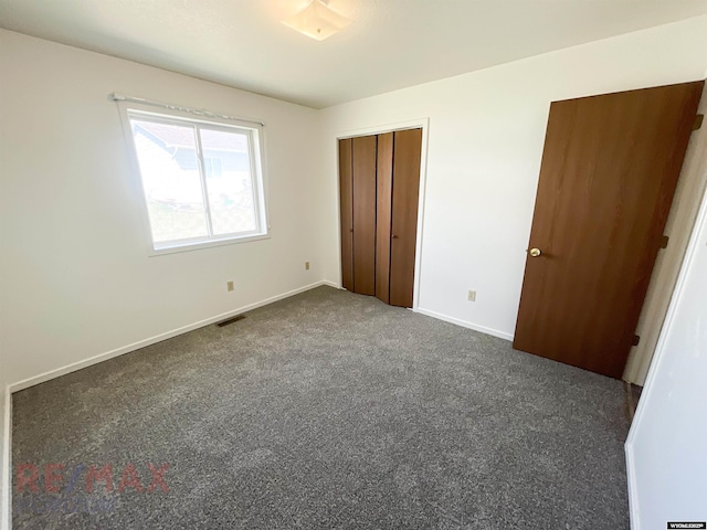 unfurnished bedroom featuring baseboards, dark colored carpet, and visible vents