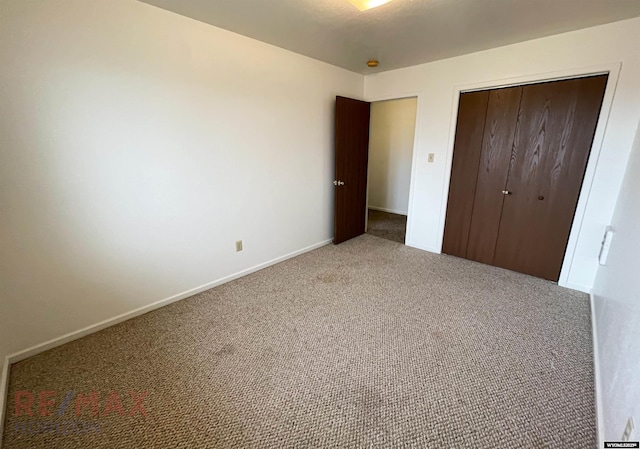 unfurnished bedroom featuring baseboards, carpet, and a closet