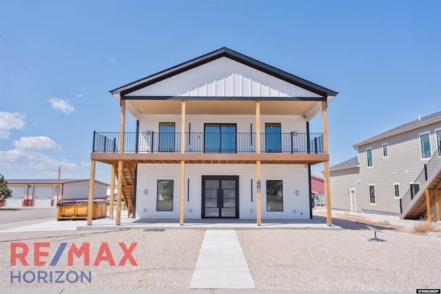 view of front of house with stairway, a balcony, a hot tub, and a patio