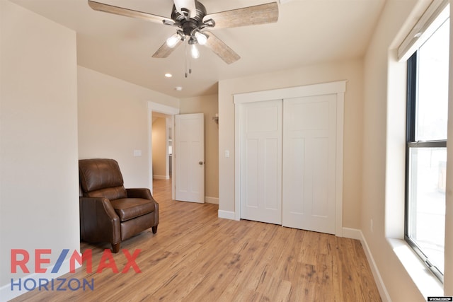 living area featuring a ceiling fan, baseboards, a healthy amount of sunlight, and light wood-type flooring