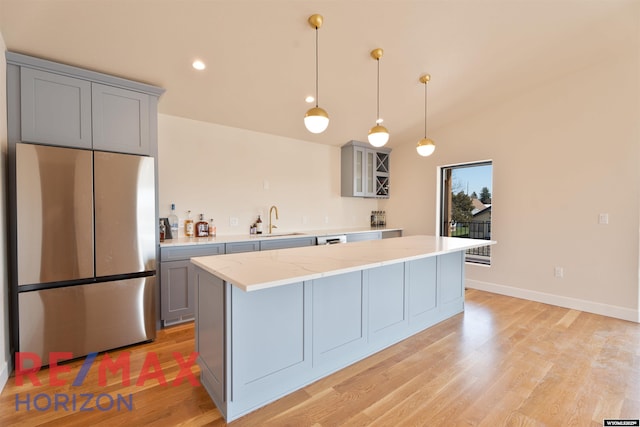 kitchen with a center island, a sink, light wood finished floors, gray cabinetry, and freestanding refrigerator