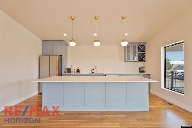 kitchen with light wood-type flooring, a center island, freestanding refrigerator, and a sink