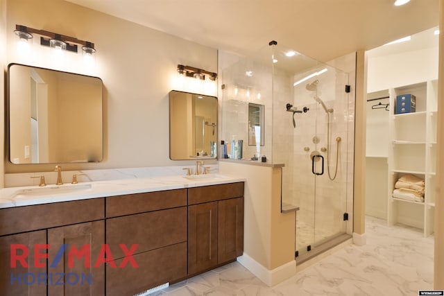 bathroom with a shower stall, marble finish floor, a sink, and double vanity