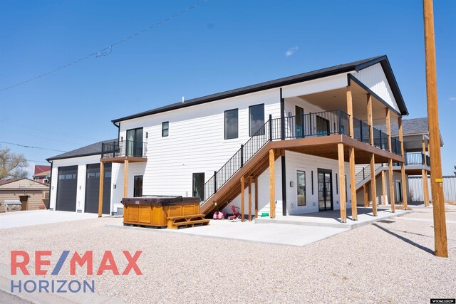 rear view of property featuring a patio area, stairs, driveway, and a hot tub