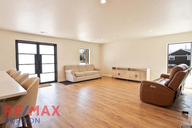 living room featuring recessed lighting, visible vents, french doors, light wood-style floors, and baseboards
