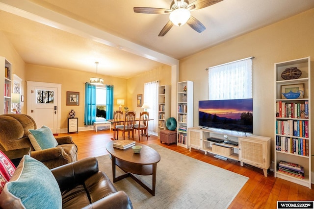 living area with built in shelves, ceiling fan, and wood finished floors