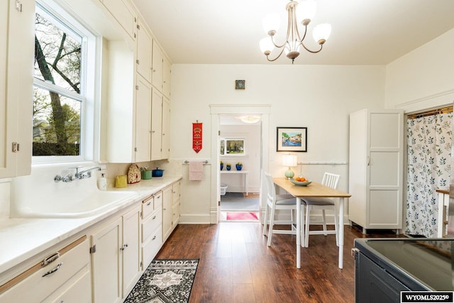 kitchen featuring a sink, white cabinets, range, light countertops, and dark wood finished floors