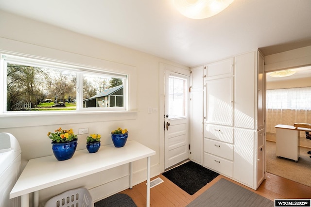 entryway with washer / dryer, wood finished floors, and visible vents
