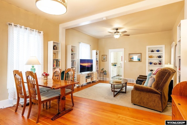 living area with visible vents, light wood-type flooring, baseboards, built in shelves, and ceiling fan