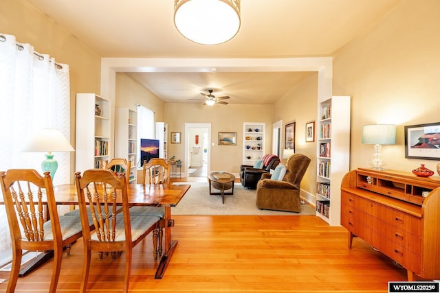 dining room with light wood-style floors, built in features, and ceiling fan