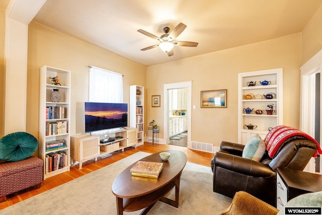 living area with wood finished floors, visible vents, and ceiling fan