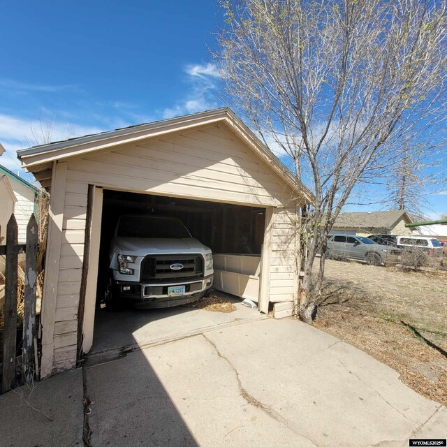 garage featuring driveway and fence