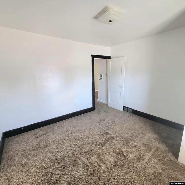carpeted empty room featuring baseboards