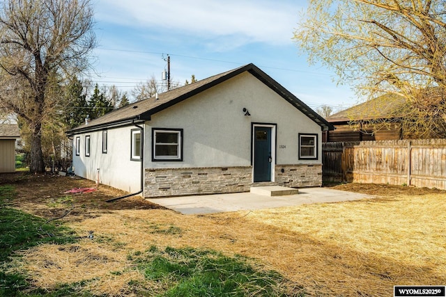 1324 Lewis St, Sheridan, WY 82801 - back of property featuring fence, a patio area, stucco siding, and stone siding