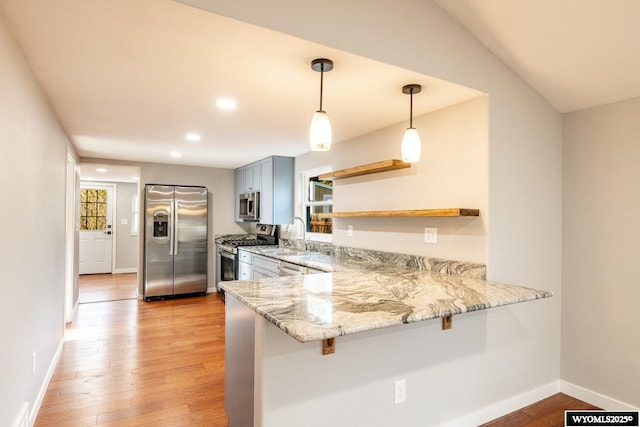 kitchen with light stone counters, a breakfast bar, stainless steel appliances, open shelves, and light wood-type flooring