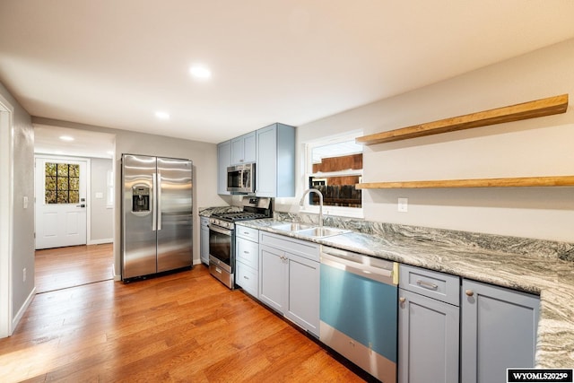 kitchen featuring recessed lighting, a sink, open shelves, light wood-style flooring, and appliances with stainless steel finishes