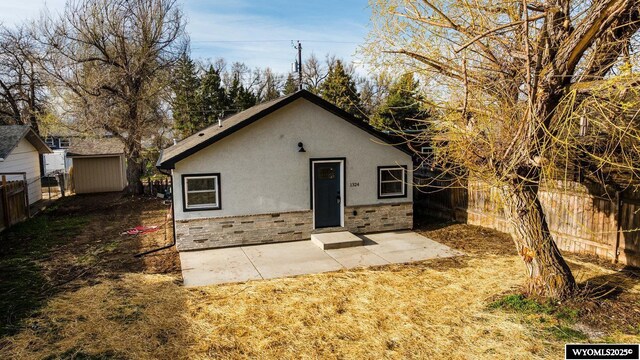 1324 Lewis St, Sheridan, WY 82801 - view of front of home featuring fence, a patio, stucco siding, and stone siding