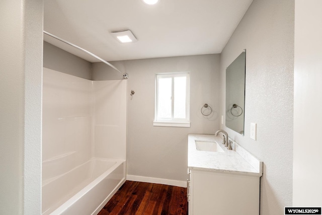 bathroom with wood finished floors, vanity,  shower combination, and baseboards